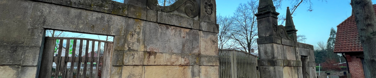 Stechinelli Tor Stechinelli Tor mit verwitterten Steinpfeilern und hölzernem Zaun unter klarem Himmel.